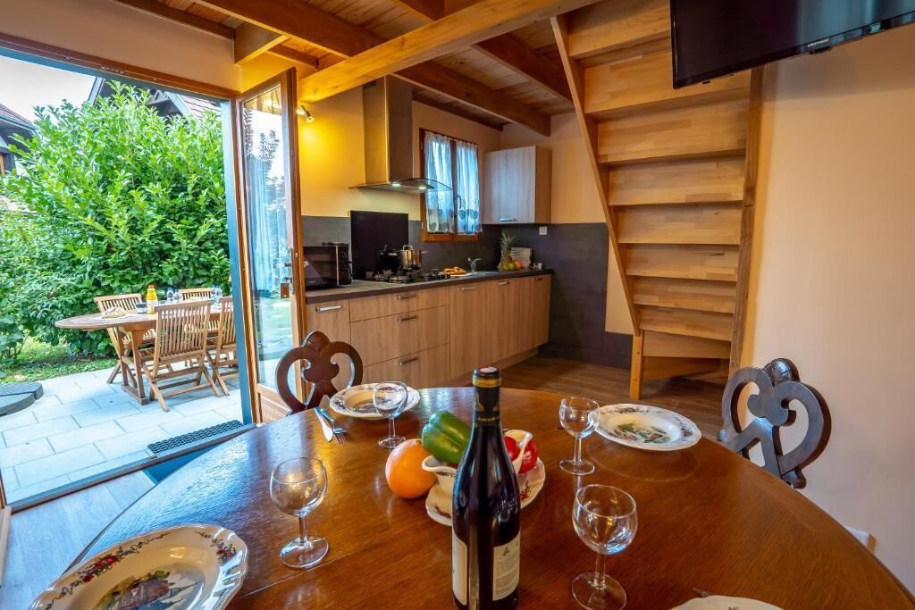 A dining area with a table set for a meal, a bottle of wine, and a kitchen in the background.