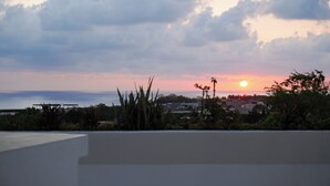 A sunset over a coastal landscape with buildings and vegetation. - Casa Pola | Tropical Loft for 2 Near Beach & La Punta (Puerto Escondido)