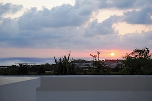 A sunset over a coastal landscape with buildings and vegetation. - Casa Pola | Tropical Loft for 2 Near Beach & La Punta (Puerto Escondido)