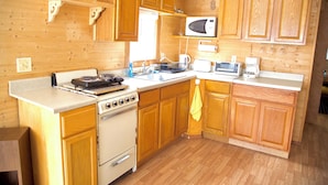 A wooden-paneled kitchen with a stove, microwave, and sink. - Pocono Comfortable 2Bedroom Stay (Gouldsboro)