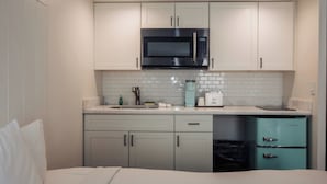 A compact kitchenette with a microwave, a sink, and a small refrigerator.
