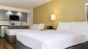 A hotel room with two beds, a kitchenette, and a bedside lamp. - Premium Kalākaua Haus Kitchenette (Honolulu)