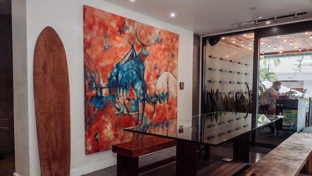 A modern interior with a large abstract painting, a wooden bench, and a glass table.