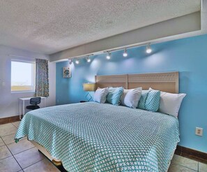 A bedroom with a bed, a desk, and a window with curtains. - 1BR Oceanfront Paradise @Camelot! (Myrtle Beach)