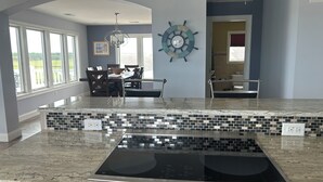Uma cozinha com uma ilha grande, um relógio de parede e um espaço de refeições com cadeiras e mesa.