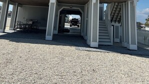 Um edifício com vários andares, uma área externa coberta, uma escadaria e um veículo ao fundo.
