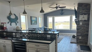 Cozinha com ilha grande, luminárias pendentes, parede em pedra e vista para o exterior.