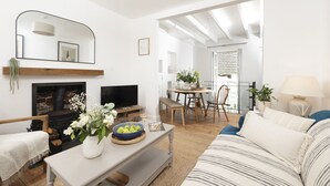 Una sala de estar con chimenea, televisor y un comedor con mesa y sillas.