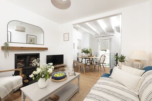 Un salon avec une cheminée, un téléviseur et un coin repas comprenant une table et des chaises.