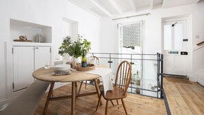 Un comedor con una mesa y sillas de madera, un florero con plantas y una botella de vino.