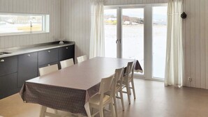 Un'area pranzo con tavolo e sedie, una finestra, un lavandino e una porta scorrevole in vetro su una zona esterna innevata.