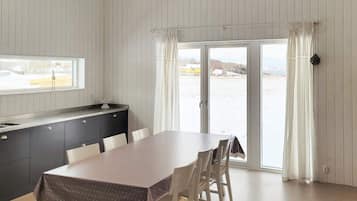 A dining area with a table and chairs, a window, a sink, and a sliding glass door to a snowy outdoor area.