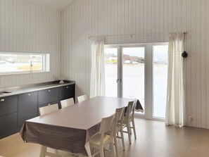 Un comedor con una mesa, sillas, una ventana, un lavamanos y un ventanal corredizo a un área exterior nevada.