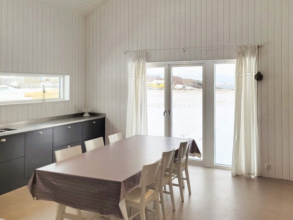 A dining area with a table and chairs, a window, a sink, and a sliding glass door to a snowy outdoor area.