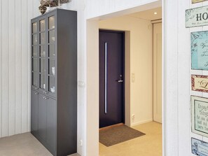 Un couloir avec une porte bleu foncé, un meuble gris aux portes vitrées et un mur orné de citations inspirantes encadrées.