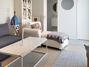 A modern living room with a sofa, a coffee table, a patterned rug, and a decorative lamp. - 5 Star Holiday Home in Ellos (Ellos)