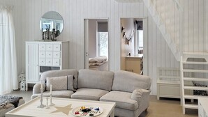 Amplia sala de estar con un sofá a rayas, una mesa de centro con diseño de estrella, una escalera blanca y vistas de un dormitorio con papel tapiz estampado.
