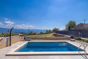 A swimming pool with a view of the sea, a stone wall, and a clear sky. - Holiday house LAVANDA with pool and panoramic seaview (Risika)