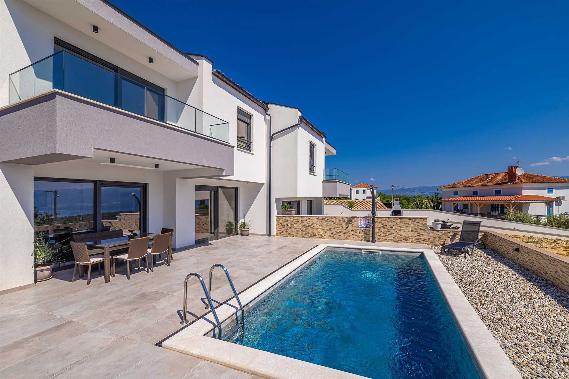 Een modern huis met twee verdiepingen, een zwembad, terras en uitzicht op de omgeving.