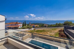 Zona residencial con vista despejada al mar, piscina y una carretera al fondo.