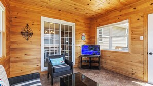A wooden-paneled room with a sofa, a chair, a TV, and a decorative wall piece. - Spacious 4BR Home Sleeps 10 I Game Room + Sunroom+ Veranda (DIEPPE)