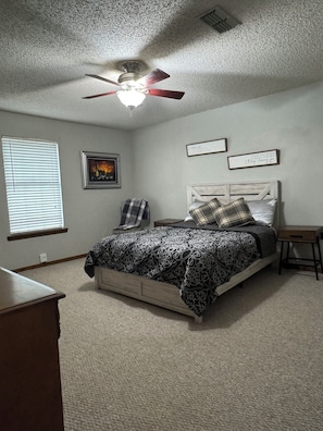 A bedroom with a bed, a ceiling fan, a window with blinds, and a framed picture on the wall. - Family and Pet Friendly Home in Benton, AR (Benton)
