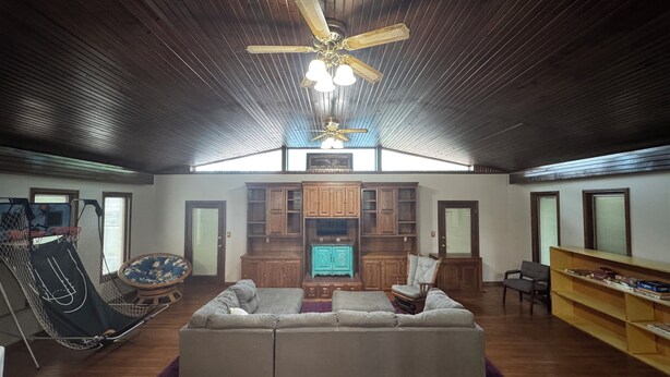 A spacious living area with a large sofa, wooden cabinets, a ceiling fan, and a television. - Family and Pet Friendly Home in Benton, AR (Benton)
