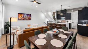 Una sala de estar moderna con sofá, mesa de comedor y zona de cocina.