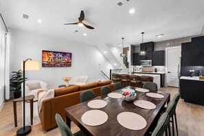 Ein modernes Wohnzimmer mit einer Couch, einem Esstisch und einer Küchenzeile.