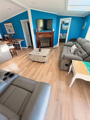Ein Wohnzimmer mit Kamin, einer Couch, einem Couchtisch und einem Fernseher.