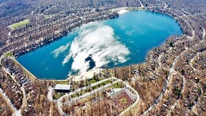 Ilmakuva järvestä, jonka ympärillä on asuinalueita, ja kuvassa näkyy muutamia rakennuksia ja teitä.