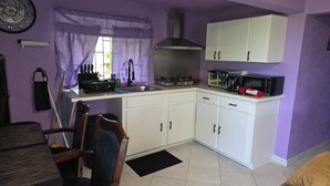 Uma cozinha compacta com armários brancos, fogão a gás, micro-ondas e pia.