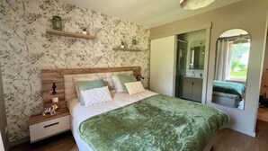 Ein Schlafzimmer mit einem Bett, Nachttischen, einem Spiegel und einem Fenster.