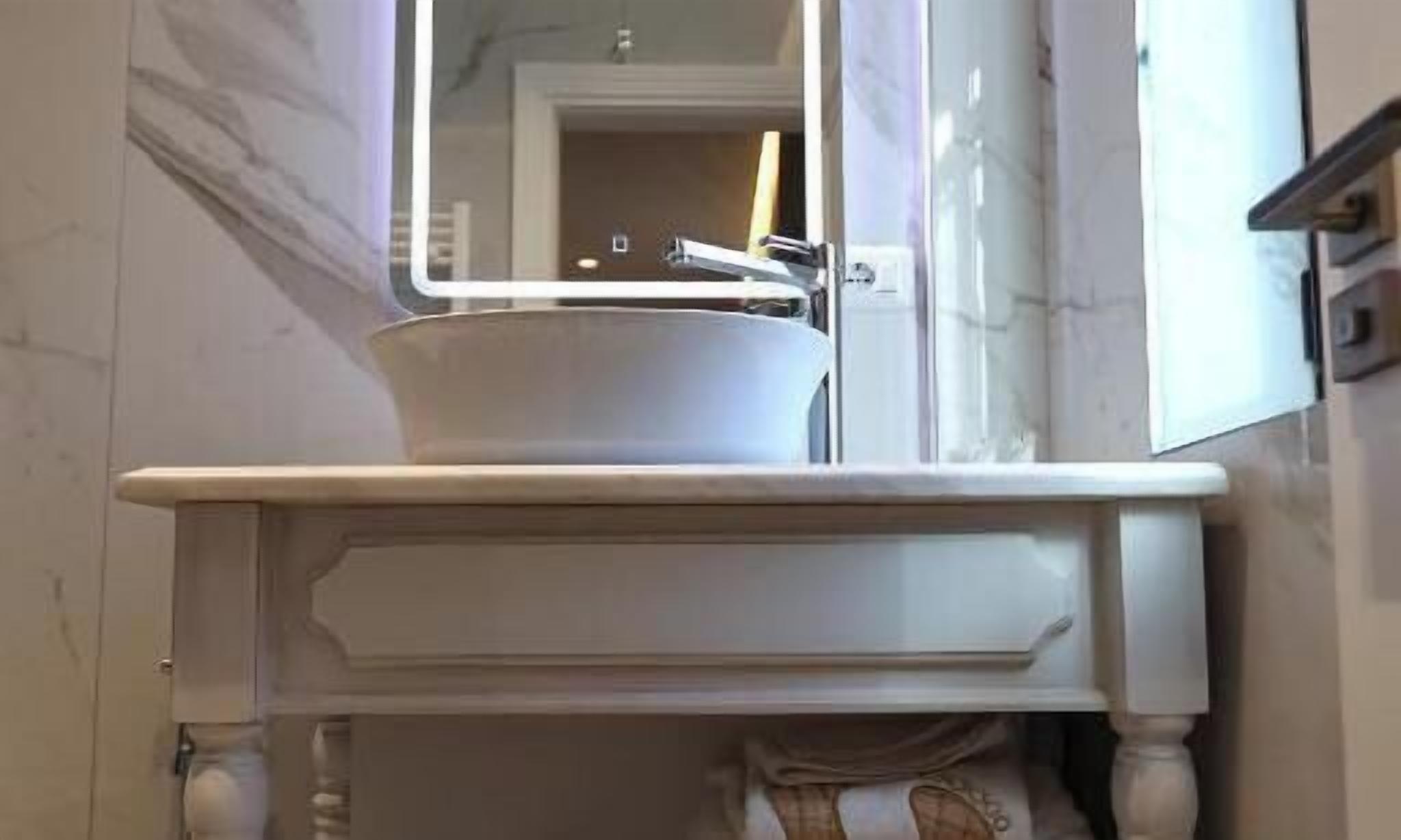 Un meuble-lavabo pour la salle de bain, comprenant un évier, un miroir et un placard.