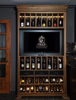 A wine rack with multiple bottles, a television screen with a logo, and a wooden cabinet.