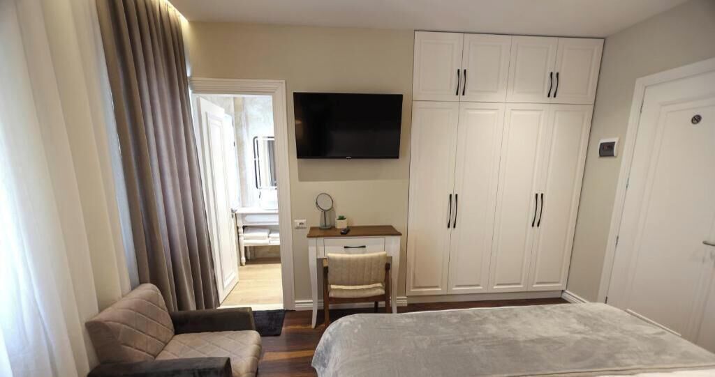 A bedroom with a bed, a desk, a chair, a TV, and a wardrobe.