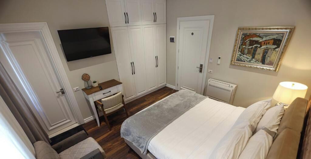 A bedroom with a bed, a desk, a television, and a wardrobe.