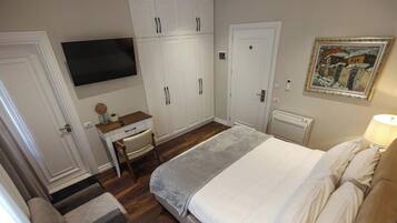 A bedroom with a bed, a desk, a television, and a wardrobe.