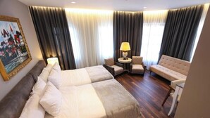 A hotel room with a bed, two armchairs, a sofa, a lamp, and a painting on the wall. - Villa Domenico Korce Old Bazaar (Korçë)