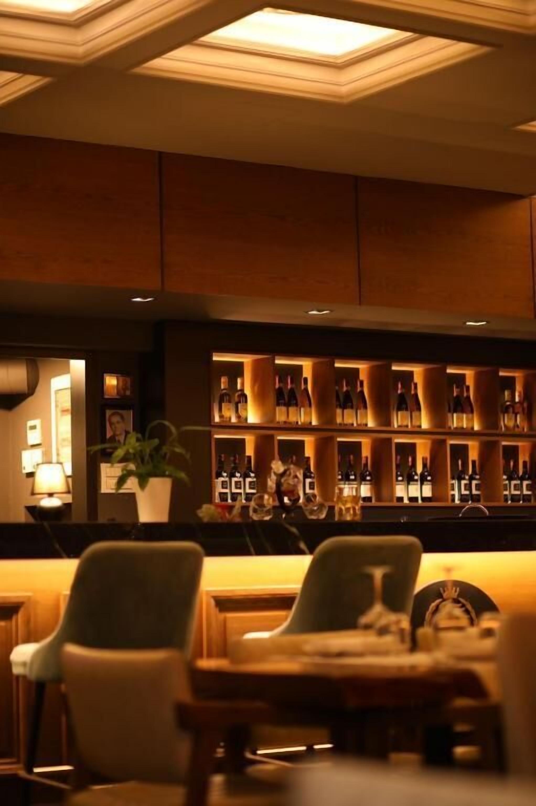 Un'area bar con posti a sedere ed scaffali pieni di bottiglie.