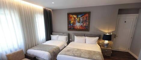Una habitación de hotel con dos camas, una silla, un cuadro en la pared y una puerta.