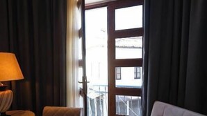 A hotel room with a sofa, a chair, a lamp, and a view of the outside. - Villa Domenico Korce Old Bazaar (Korçë)