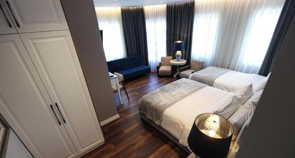 A hotel room with a bed, a desk, a chair, and a sofa.