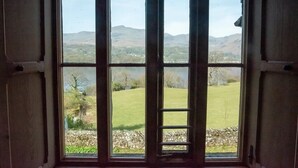 Una habitación con un ventanal que ofrece vistas a un campo verde y colinas distantes.