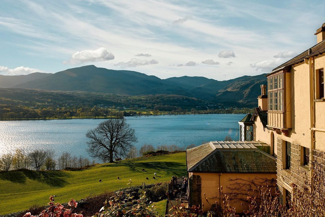 A lakeside view with a building featuring a stone facade and a balcony.