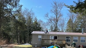 A house with a metal roof, a wooden deck, and a fenced yard. - Sandy Toes Retreat,stunning view & just 25 steps to a sandy beach Lake Michigan. (Cedar River)