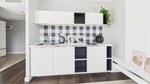Uma cozinha moderna com armários brancos, painel de backsplash quadriculado e forno embutido.