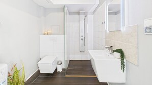 Uma casa de banho moderna com chuveiro, sanita e lavatório.