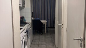 A narrow hallway with a washing machine, a small table, and a chair. - T2 Sanary near sea (Sanary-sur-Mer)