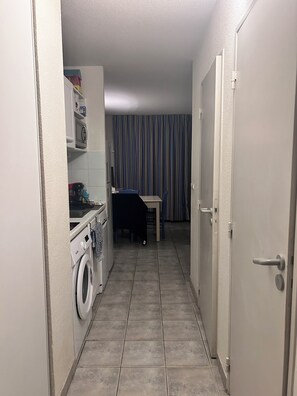 A narrow hallway with a washing machine, a small table, and a chair. - T2 Sanary near sea (Sanary-sur-Mer)